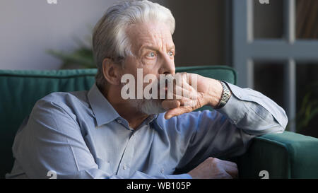 Pensive thoughtful senior man looking away sitting alone at home Stock Photo