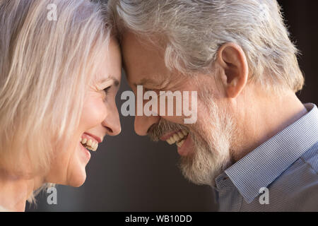 Happy old couple bonding touching foreheads laughing, closeup side view Stock Photo