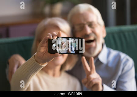 Happy old couple taking selfie on cellphone, focus on display Stock Photo
