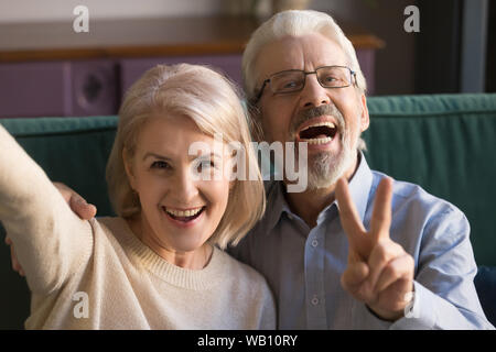 Smiling funny older couple take selfie, phone cam view Stock Photo