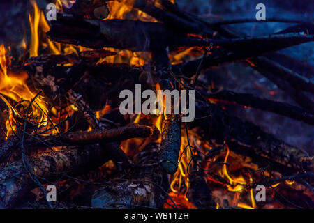 bright fire in the fireplace, in the foreground burned firewood Stock Photo