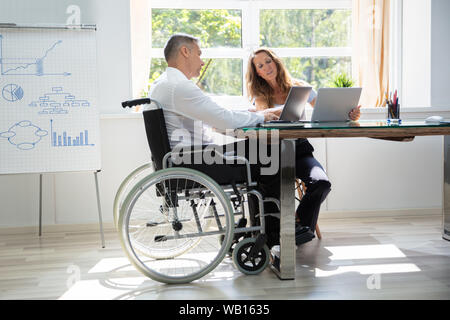 Two Workers Using Laptop Working Together At Office Stock Photo