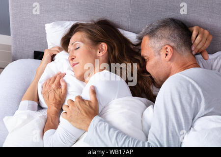 Mature Loving Couple Sleeping On Bed With White Blanket Stock Photo