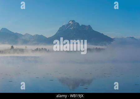 Germany, Bavaria, Allgaeu, Ammergau Alos, Mountains at Lake Hopfensee and fog Stock Photo