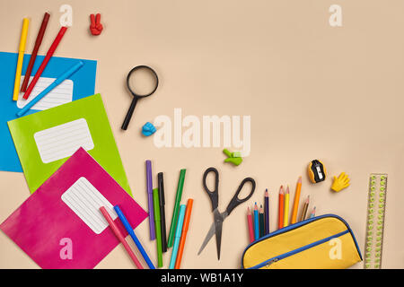 Flat lay photo of workspace desk with school accessories or office supplies on pink background. Stock Photo