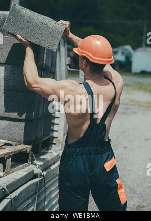 Construction concept. Man carry bricks for construction works. Builder ...
