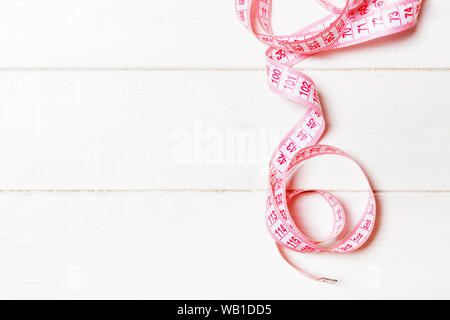 Top view of measure tape curtailed into a spiral with copy space. Concept of sewing accessory or healthy diet on wooden background. Stock Photo