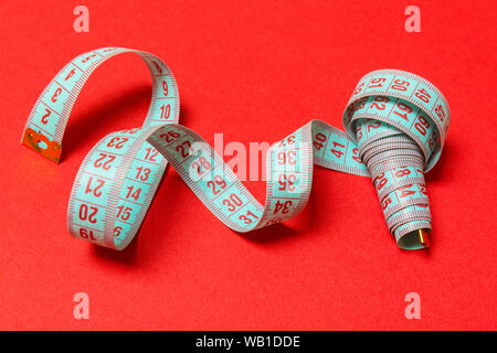 Perspective view of spiral measuring tape on red background. Close up of slimming concept. Stock Photo