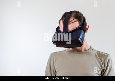 Caucasian man in t-shirt wearing virtual reality goggles on white background. Future technology concept. Stock Photo