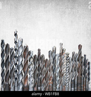 Old rusty drill bits of different sizes isolated on gray grunge background with copy space on top, construction background Stock Photo