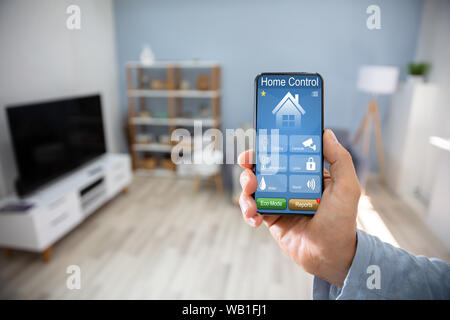 Man Using Smart Home Application On Mobile Phone Stock Photo