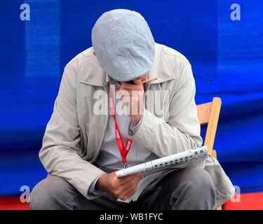 Edinburgh, UK. 22nd Aug, 2019.  Artists and performers around the Mound on Princess Street Edinburgh.  An artist takes time out to do the crossword. Credit: Chris McNulty/Alamy Live News Credit: Chris McNulty/Alamy Live News Stock Photo