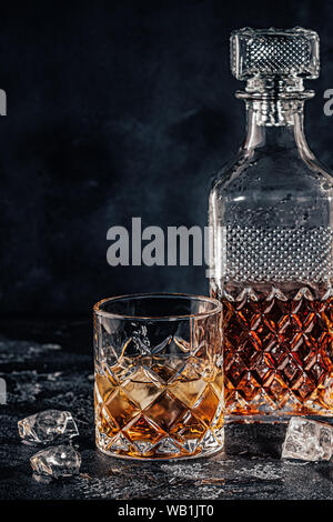 Glasses of the whiskey with a square decanter on a black stone background. Stock Photo