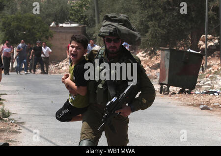 Nablus, Palestine. 23rd Aug, 2019. An Israeli soldier detains a Palestinian child during clashes, after a protest against the expanding of Jewish settlements in Kufr Qadoom village near the West Bank city of Nablus, Aug. 23, 2019. Credit: Xinhua/Alamy Live News Stock Photo