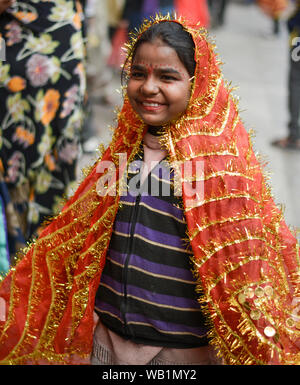 Girl child beggar smiling at camera in colorful religious dress. Stock Photo