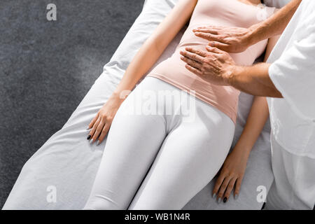 cropped view of healer standing near woman and holding hands above her stomach Stock Photo