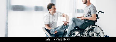 panoramic shot of Physiotherapist massaging leg of patient in wheelchair in hospital Stock Photo