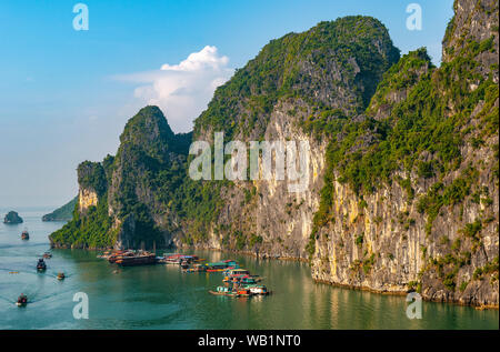 A floating village among the geologic karst rock formations of Halong Bay at sunset, North Vietnam. Stock Photo