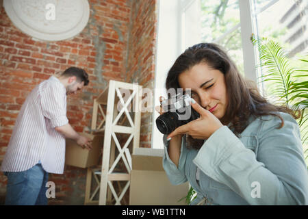 Build the future together. Young couple moved to a new house or apartment. Look happy and confident. Family, moving, relations, first home concept. Making photo, laughting while unpacking their things. Stock Photo