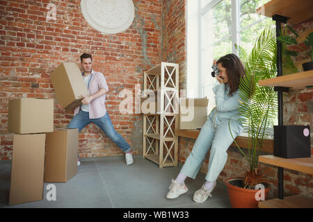 Build the future together. Young couple moved to a new house or apartment. Look happy and confident. Family, moving, relations, first home concept. Making photo, laughting while unpacking their things. Stock Photo