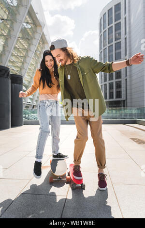 cheerful woman and man riding on skateboards Stock Photo