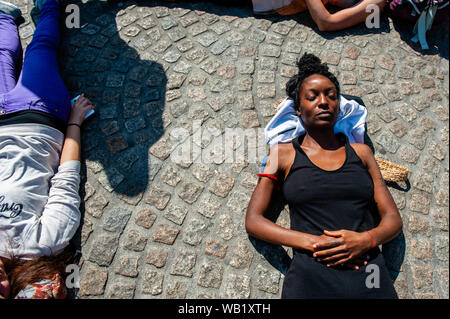 A black woman lies on the ground as she takes part during the protest.Extinction Rebellion group activists in Amsterdam organized a demonstration in solidarity with rainforest protectors and Amazon activists across the world. Hundreds of people gathered around the Dam square to show their support. Stock Photo
