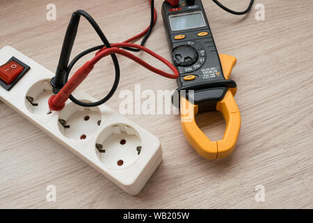 Clamp meter with Power strip on the wooden table Stock Photo