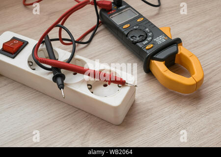 Clamp meter with Power strip on the wooden table Stock Photo