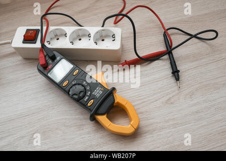 Clamp meter with power strip on the wooden table Stock Photo