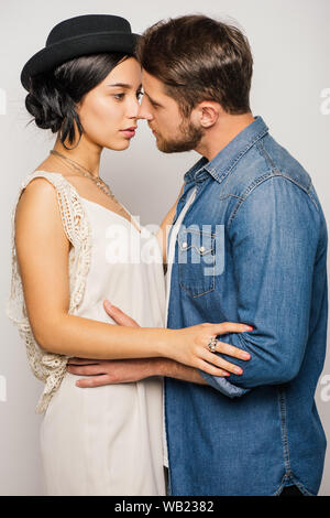 two young people in stylish clothes hugging and trying to kiss on white background Stock Photo