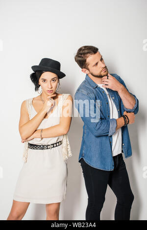 handsome man looking away and beautiful girl in fashionable clothes looking at camera while posing Stock Photo