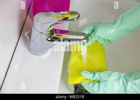 Female hands gloves cleaning cloth in bathroom sink.