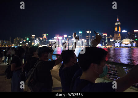 Protesters shine their phone lights while facing the harbour during the demonstration.Protesters held hands to create long human chains in peaceful protest against the extradition bill. Some protesters carried various placards asking and thanking other countries for their support while others also shined their phone lights as a sign of unity and peace. Stock Photo