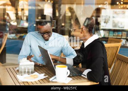 Black  African American coworkers doing digital teamwork arround a coffee cup Stock Photo
