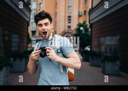 handsome man in t-shirt holding digital camera and looking at camera Stock Photo