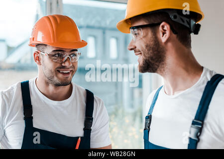happy repairmen in helmets and goggles looking at each other Stock Photo