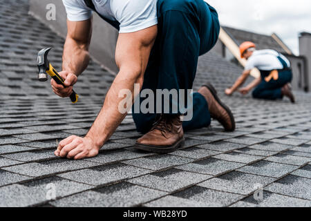 cropped view of repairmen in uniform working on rooftop Stock Photo