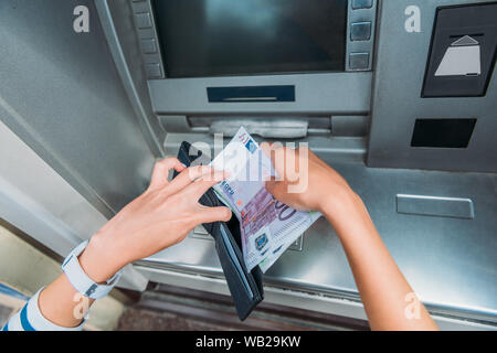 top view of woman putting money in wallet near atm machine Stock Photo