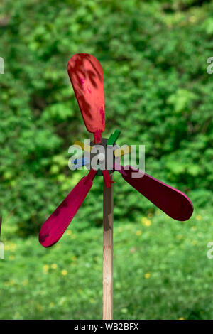children's toy windmill, made and painted by the children in the colors of the rainbow, forgotten in the spring forest Stock Photo