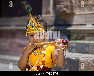 A kid dressed as lord Krishna playing a flute during the celebration.Krishna Janmasthami is an annual Hindu festival also known as Janmasthami, which is celebrated to mark the birth of lord Krishna, an eighth avatar of lord Vishnu. Stock Photo