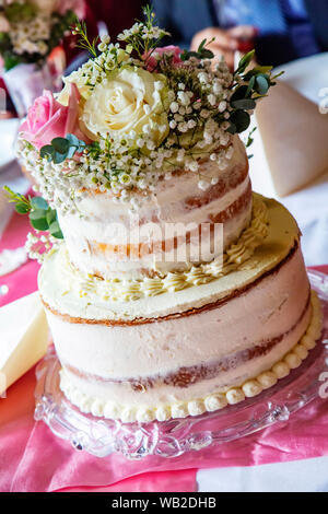 Wedding cake placed on a table with real flowers Stock Photo