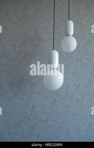 The structure of concrete is gray. Creative vintage background. Structural plaster. Modern lights in the form of a white ball on a long wire Stock Photo