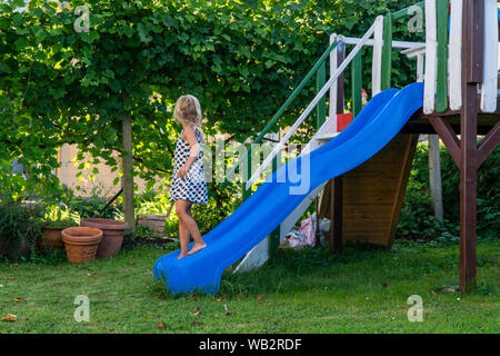 Wide photo of happy young blonde girl playing in colorful playground for kids. Child play in children's slide Stock Photo