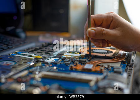 Technician repairing broken laptop notebook computer with screwdriver Stock Photo