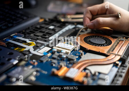 Technician repairing broken laptop notebook computer with screwdriver Stock Photo