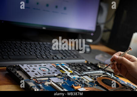 Technician repairing broken laptop notebook computer with screwdriver Stock Photo