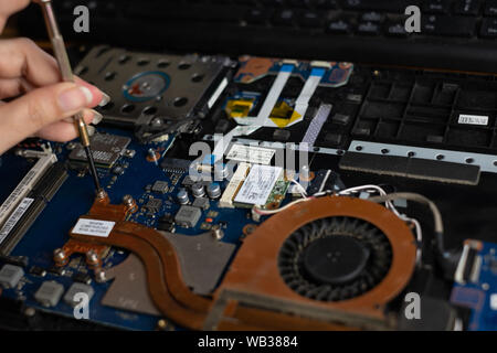 Technician repairing broken laptop notebook computer with screwdriver Stock Photo