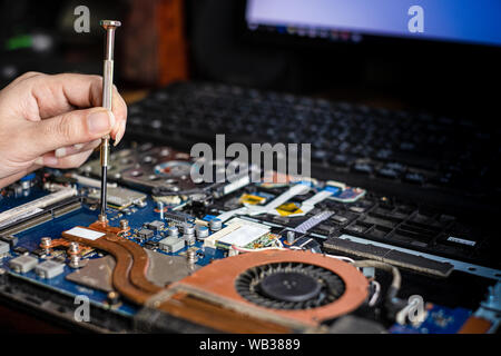 Technician repairing broken laptop notebook computer with screwdriver Stock Photo