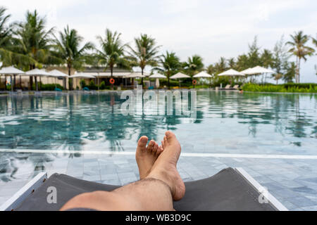 Woman legs relaxing on chair at swimming pool Stock Photo