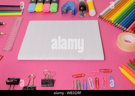 School supplies on pink board background, wit open notebook. Education, back to school concept with copy space Stock Photo